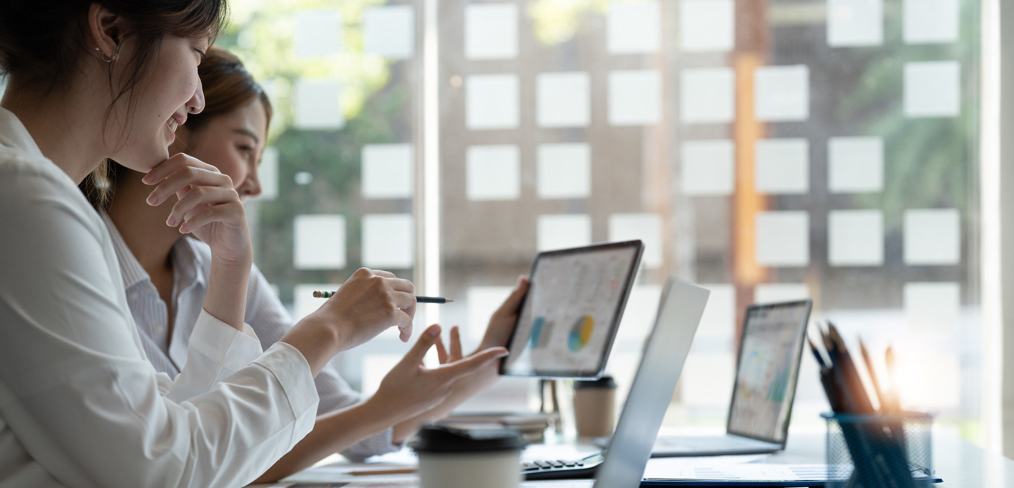 Two colleagues reviewing business data on a monitor
