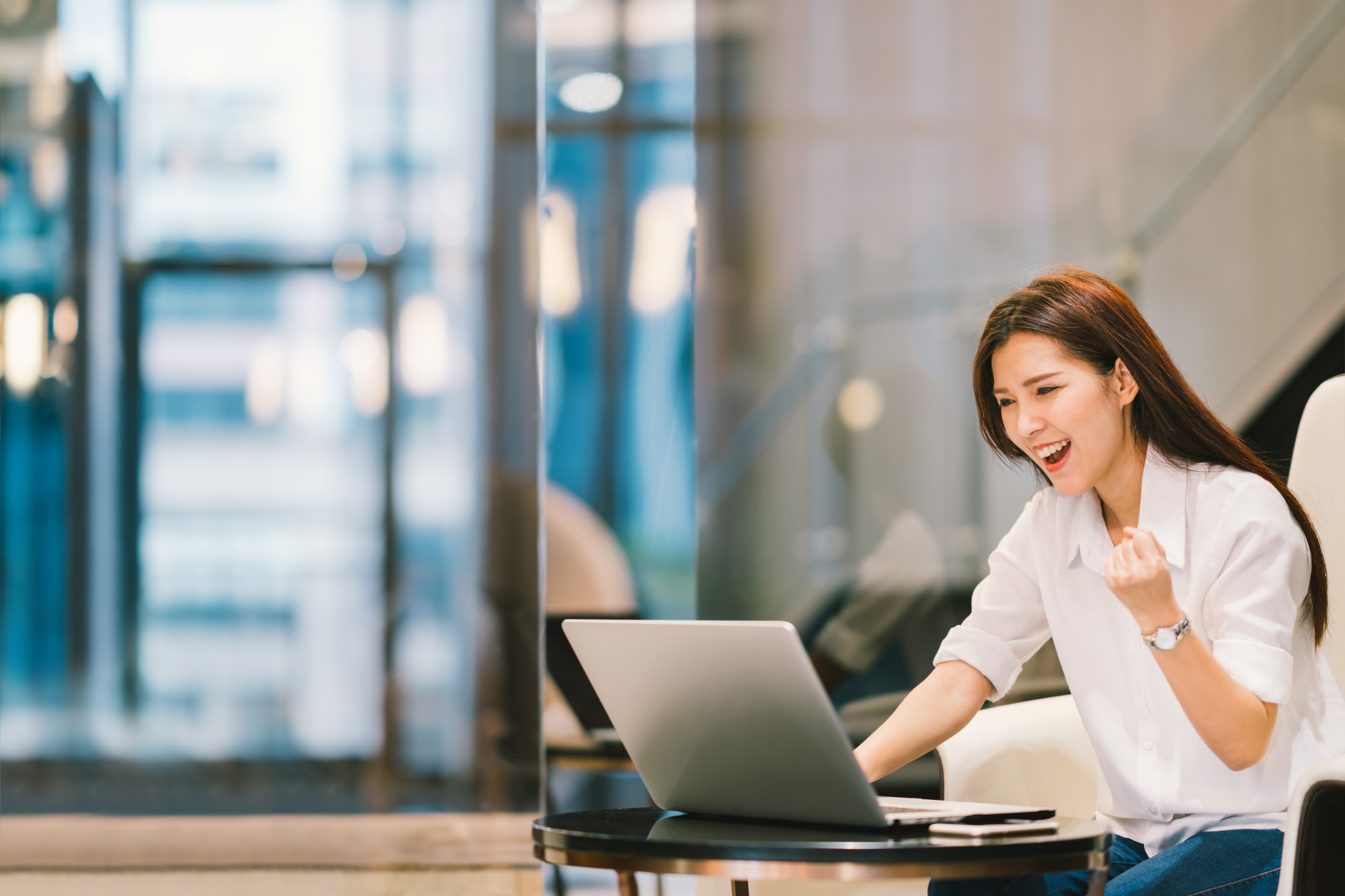 Woman standing in front of laptop in a success pose
