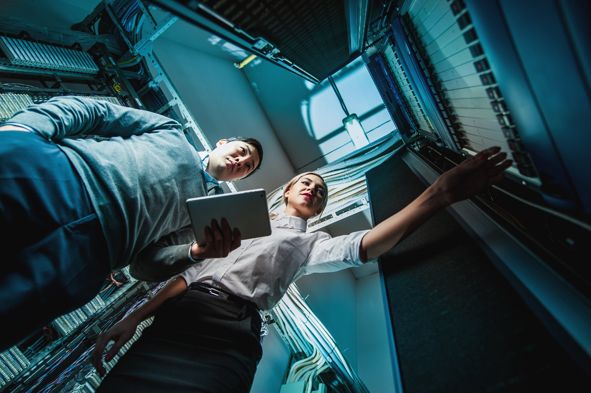 Male and Female Techs in Network Server Room Holding Tablet